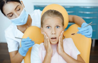 Doktor, modern ofiste korkmuş küçük bir çocukla çalışıyor.