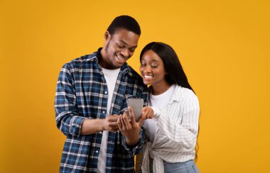 Mutlu Afrikalı genç Amerikalı karı ve koca akıllı telefondan mobil uygulamayla izliyor.