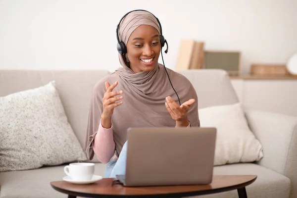 Trabajo en línea, comunicación, educación. Negro musulmana mujer en hijab tener videollamada en el ordenador portátil en casa — Foto de Stock