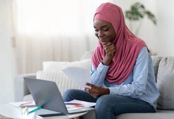 Sonriente mujer negra musulmana usando el ordenador portátil y la paleta de colores, la elección de diseño de interiores — Foto de Stock