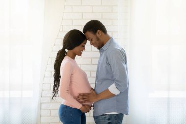 Yakışıklı siyahi adam hamile karılarının karnına dokunuyor.