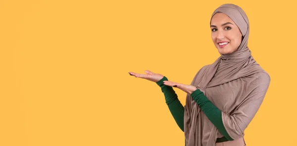 Perempuan Muslim Dalam Hijab Menampilkan Salinan Ruang samping, Latar Belakang Kuning — Stok Foto