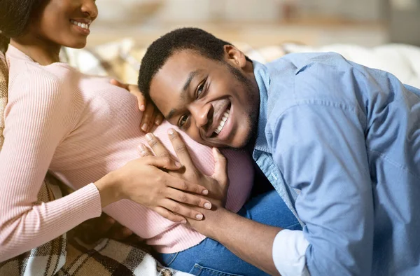 Pria kulit hitam yang bahagia memeluk perut pacarnya yang sedang hamil dan mendengarkan bayi-bayi yang belum lahir di rumah — Stok Foto