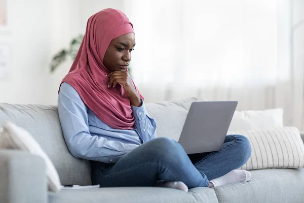 Pensativo negro musulmán freelancer femenino con portátil en casa lluvia de ideas en el proyecto — Foto de Stock
