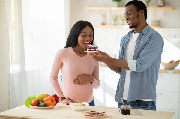 Positiv afroamerikansk kille som erbjuder läcker tårta till sin gravida flickvän hemma — Stockfoto