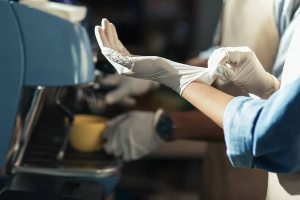 Afroamerikanischer Barkeeper zieht Handschuhe an, um an Espressomaschine zu arbeiten und Kaffee zum Mitnehmen für Kunden zuzubereiten — Stockfoto