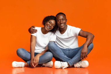 Kaygısız Afrikalı çift yerde oturuyor ve sarılıyorlar.