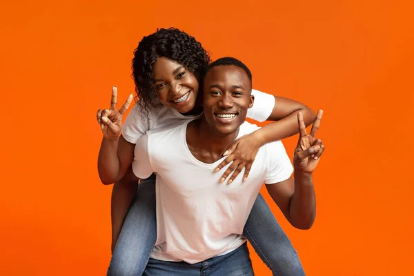 Щасливі чорні коханці позують на помаранчевому студійному фоні — стокове фото