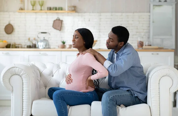 등의 통증으로 고통을 겪고 있는 흑인 여성 이사랑 많은 남편이 집에서 어깨를 마사지하고 있다 — 스톡 사진