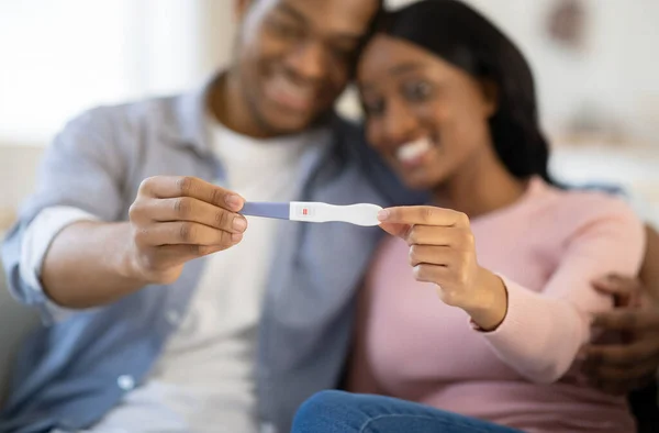 Mladý balck pár ukazuje pozitivní těhotenský test doma, selektivní zaměření na ruce — Stock fotografie