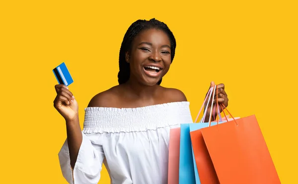 明るい黒女性でショッパーバッグとクレジットカード以上イエロー背景 — ストック写真