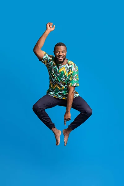 Funny black man in african costume jumping in the air