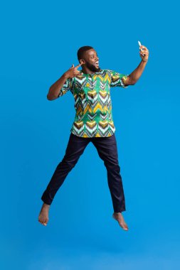 Afrikalı kostümlü mutlu siyah adam selfie çekiyor.