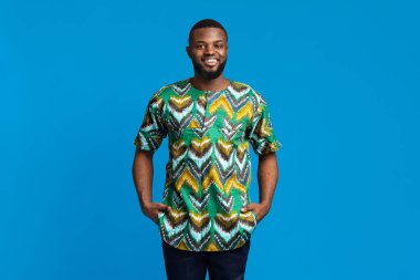 Mavi arka planda gülümseyen yakışıklı siyah adam.