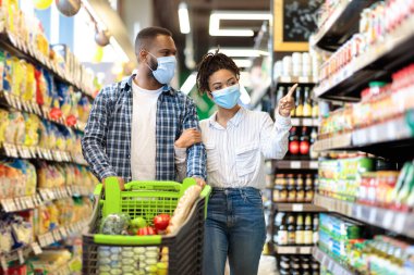 Süpermarkette koruyucu maskeli Afrikalı çift market alışverişi yapıyor.