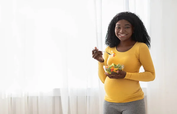 Lycklig gravid svart kvinna äter färsk sallad hemma — Stockfoto