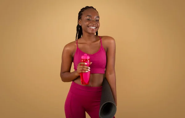 Αθλητικός τρόπος ζωής. Μαύρη γυναίκα σε αθλητικό ντύσιμο εκμετάλλευση Fitness Mat και μπουκάλι νερό — Φωτογραφία Αρχείου