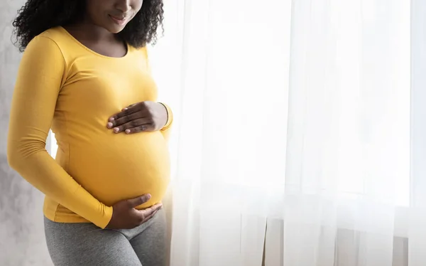 Обрізана чорна вагітна леді стоїть біля вікна — стокове фото