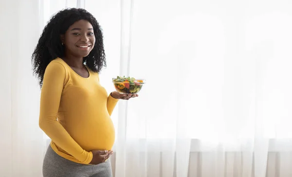 Весела африканська вагітна леді тримає миску з салатом — стокове фото