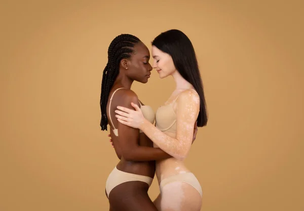 Дві красиві жінки з різними типами шкіри позують в нижній білизні, бежевий фон — стокове фото