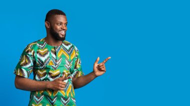 Afrikalı kostümlü heyecanlı siyah adam boş yeri işaret ediyor.