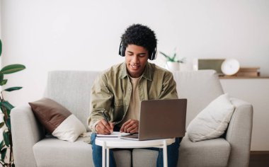 Web tabanlı eğitim konsepti. Online dizüstü bilgisayar dersi sırasında kulaklık takan pozitif genç öğrenci.