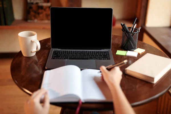 Žena sedí za stolem pomocí notebooku s prázdnou obrazovkou, maketa — Stock fotografie