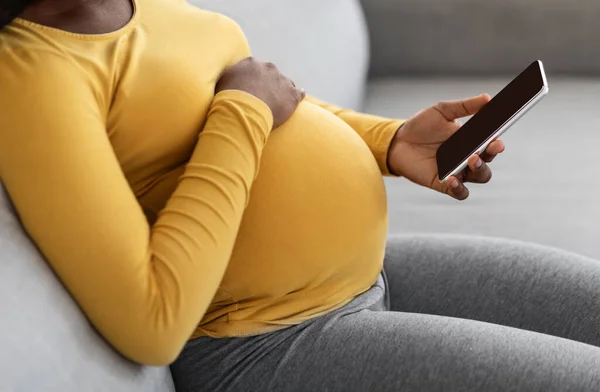 Zwarte zwangere vrouw met mobiele telefoon met leeg scherm — Stockfoto