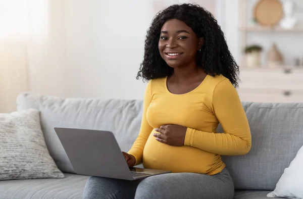 Чернокожая беременная женщина использует ноутбук дома — стоковое фото