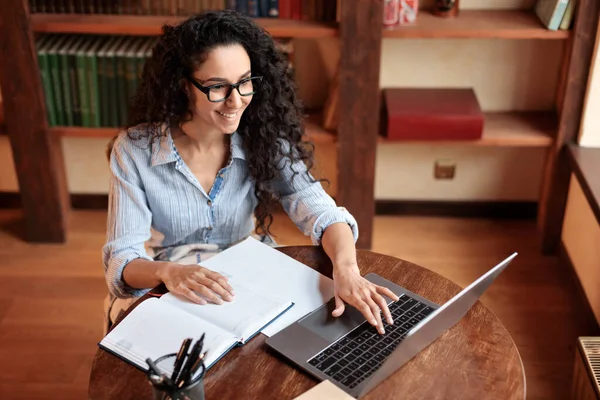 Kvinna som sitter vid skrivbordet, använder dator och skriver på tangentbordet — Stockfoto