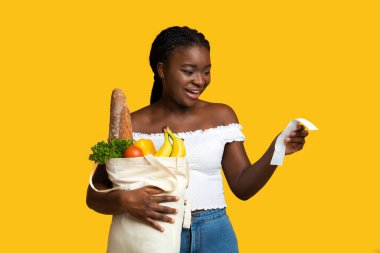 Alışveriş Ekonomisi. Market poşeti ve makbuz taşıyan mutlu siyah kadın.