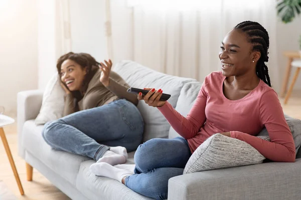 Dos lindas damas negras viendo televisión en el sofá — Foto de Stock