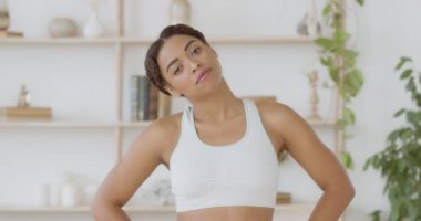 Fitness eğitimi. Genç Afro-Afrikalı Amerikalı bayan evde spor yapmadan önce boynunu ısıtıyor.