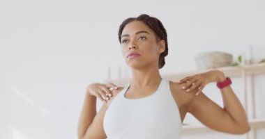 Fiziksel pislikler. Evde antremandan önce omuzlarını ısıtan odaklanmış Afro-Amerikan sporcu kadının kapalı bir portresi.