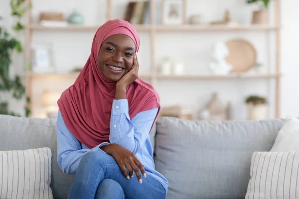 Szerény fekete muszlim nő fejkendőben Relaxáló kanapén otthon — Stock Fotó