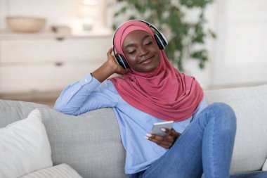 Gevşemiş Müslüman Kadın Akıllı telefon ve kulaklıkla müzik dinlemekten zevk alıyor.