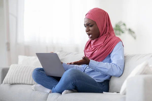 Problemas informáticos. Mujer árabe enojado que tiene problemas con el ordenador portátil en casa, molesto de la mala conexión a Internet, espacio libre — Foto de Stock