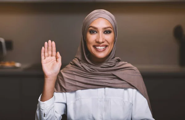 Musulmana signora in hijab onda mano seduta in cucina — Foto Stock