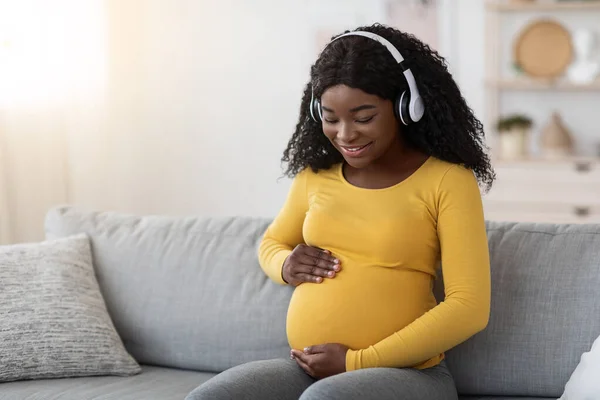 Happy těhotná černošky žena poslech hudby ve sluchátkách — Stock fotografie
