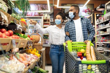 Afro-Amerikalı çift birlikte market alışverişi yapıyor. Yiyecek alıyorlar.