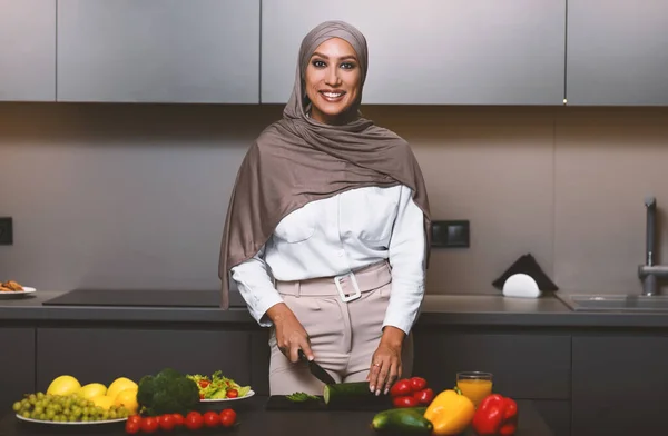 Felice signora musulmana che cucina in cucina rendendo insalata per la cena — Foto Stock