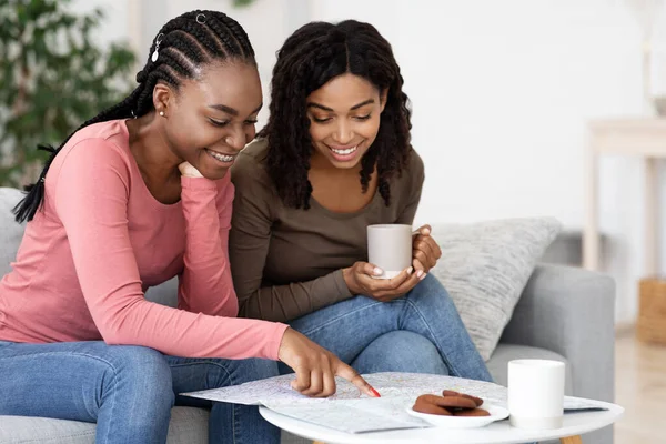 Радостные африканские американские подружки смотрят на карту, когда пьют кофе. — стоковое фото
