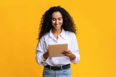 Gülümseyen esmer kadın dijital tablet kullanıyor, sosyal ağları tarıyor.