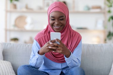 Genç Siyahi Müslüman Kadın Smartphone 'da Sosyal Ağlara Bakıyor, Evde Rahatlıyor