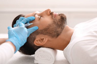 Kozmetik uzmanı orta yaşlı bir adam için kaldırma işlemleri yapıyor.