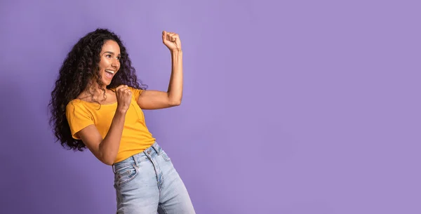 Euphoric brunette woman emotionally celebrating success, raising fists and exclaiming with excitement