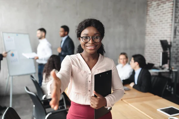 Mujer de negocios africana estirando la mano para el apretón de manos de pie en el cargo —  Fotos de Stock