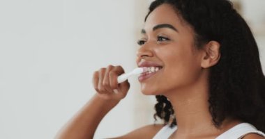 Genç Afro-Amerikan kadın portresi banyoda dişlerini fırçalarken, ağır çekimde