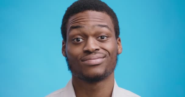 Close up retrato de homem negro bobo com expressão facial incerta, rosto sorridente e cabeça tremendo — Vídeo de Stock