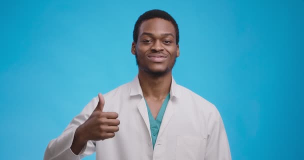 Koncepcja szczerej aprobaty. młody czarny medyczny lekarz gestykulując kciuk w górę i uśmiechając się do kamery — Wideo stockowe